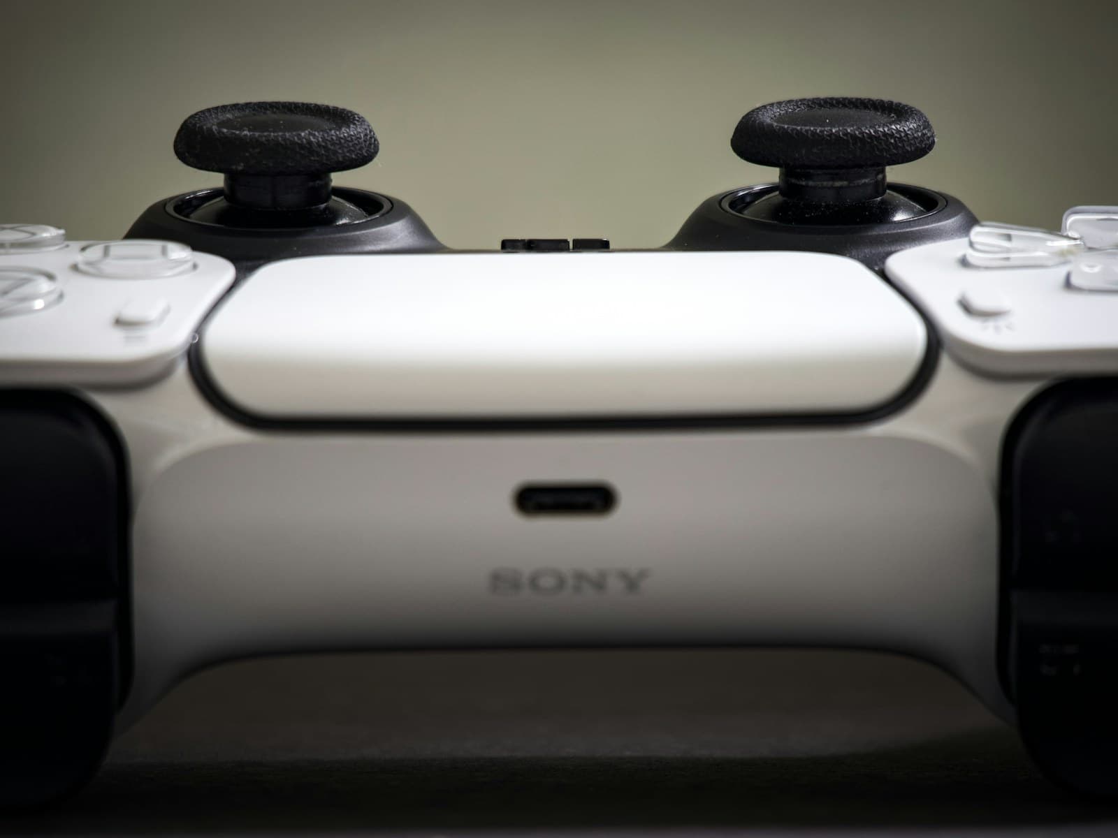 Le haut d’une DualSense blanche et noire : les deux joysticks, la tranche du pavé tactile et le port USB-C