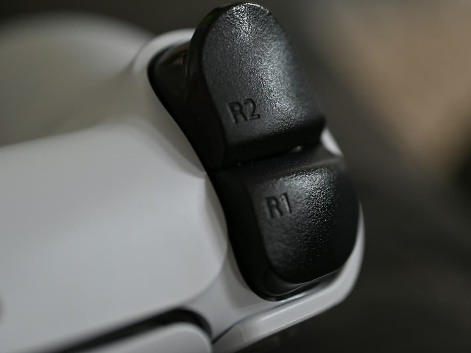 Gros plan sur les gâchettes R1 et R2 d’une manette DualSense blanche