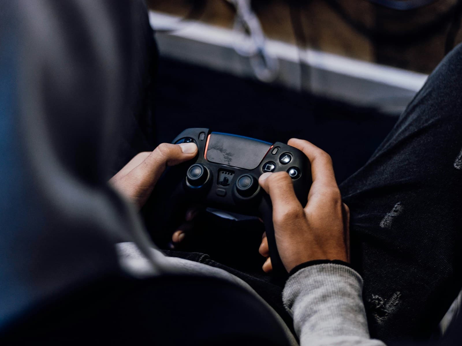 Un joueur tient une DualSense noire, les pouces sur les deux joysticks